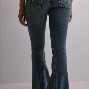 True Religion lowesisy bootcut jeans - Säljer ett par ikoniska blå bootcut jeans från True Religion, med unik söm baktill. Köpte på Nelly för 1600kr. Dem är knapt andvända vilket är andledningen till att jag säljer dem och dem har ändat små defekter nedtill vid benen.💗