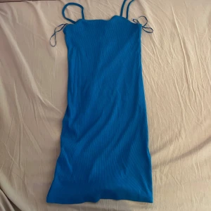 Blå ribbad kortklänning från NEW YORKER  - Supersnygg tajt blå ribbad klänning med smala axelband och figurnära passform. Materialet är mjukt och stretchigt för en bekväm känsla. Storlek 36 