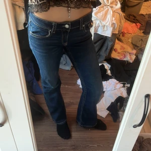 Mörkblå bootcut jeans med kontrastsömmar - Säljer ett par mörkblå jeans med bootcut-modell och snygga kontrastsömmar. Jeansen har låg midja, klassiska fickor fram och bak samt detaljerade bakfickor. Från lager 157