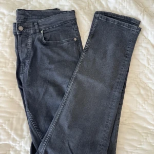 Svarta jeans från J.Lindeberg - Snygga svarta jeans från J.Lindeberg med klassisk femficksdesign och silverfärgade detaljer. Jeansen har rak passform och är tillverkade i mjukt bomullsmaterial med en stilren look. Perfekta för dig som gillar en clean och tidlös stil.