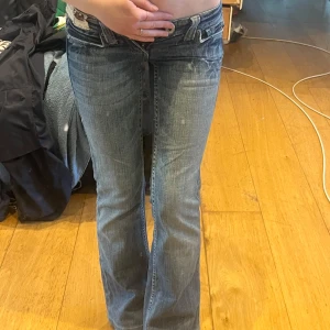 Miss Me bootcut jeans med detaljer - Snygga blå bootcut jeans från Miss Me med låg midja och slitna detaljer. Bakfickorna har unika broderier och patchwork i brunt och vitt. Jeansen har klassisk femficksdesign och cool tvättad look. Perfekta för dig som vill sticka ut lite extra.