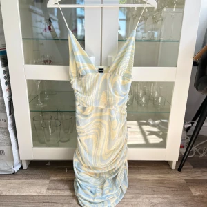 Mönstrad sexig klänning med scrunch detalj - En ny och oanvänd jättefin, snygg och sexig ljusgul, ljusblå mönstrad cami klänning med scrunch detalj i midjan i storlek S från SHEIN SXY. Yttre tyget är i mesh-tyg, 94% Polyester, 6% Elastan och innertyget är i 100% Polyester. Säljs pga att den blivit för liten. FÖRST TILL KVARN!