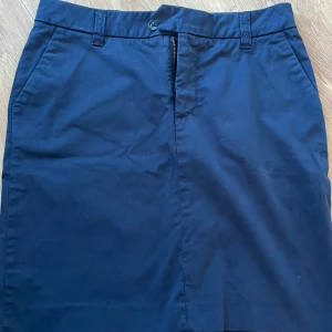 Mörkblå bomullskjol från Boomerang - Klassisk mörkblå kjol från Boomerang i bomull. Kjolen har fickor fram, bälteshällor och en snygg knapp- och dragkedjestängning. Rak modell som slutar ovanför knäet, perfekt till en chill och stilren look.