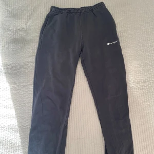 Mörkblåa  mjukisbyxor från Champion - Säljer ett par mörblåa mjukisbyxor från Champion med elastisk midja och muddar vid bensluten. Byxorna har en broderad Champion-logga på benet. Perfekta för en avslappnad stil. Säljer för 100 kr + frakt 