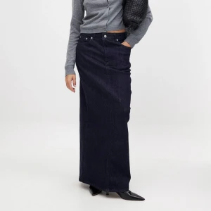 Mörkblå jeanskjol - Snygg mörkblå lång jeanskjol med slits bak. Perfekt för en stilren look. Kjolen har en klassisk design med fickor och knappar framtill. Köptes på Nakd, den är slutsåld!! Köpt för 549 kr nypris