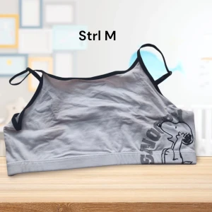 Vit Snoopy bh-topp strl M - Säljer en vit topp med svart kant och ett tryck av Snoopy på framsidan. Toppen har smala axelband och är perfekt för en avslappnad stil. Den är gjord i ett mjukt material som känns skönt mot huden. Oanvänd med prislappen kvar. Se också mina andra annonser för liknande plagg och chans att köpa bundles med rabatt och samfrakt.