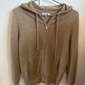 Beige hoodie från Soft Goat - Säljer en stilren beige hoodie från Soft Goat. Den har dragkedja framtill och en mysig huva med knytband. Perfekt för kyliga dagar med sina långa ärmar och mjuka material. Den är andvänd bara några få gånger och är som ny,