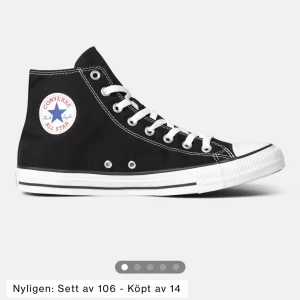 Svarta Converse All Star sneakers - Klassiska svarta Converse All Star sneakers i hög modell med vit sula och snörning. Perfekta för en avslappnad stil och passar till det mesta. Den ikoniska loggan syns på sidan av skon.