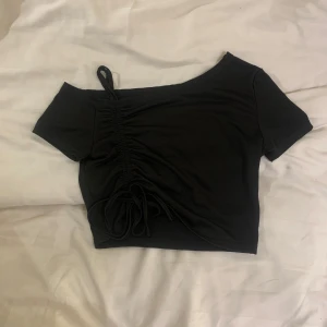 Svart oneshoulder topp - Snygg svart nästan som oneshoulder topp med snörning på sidan. 