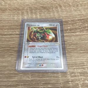 Pokémon Kort: Rayquaza ex ULTRA RARE  - Säljer detta Rayquaza kort från 2005 då jag inte har intresse för pokémon längre. Kortet är i dubbel plastficka en mjuk och en hård och så klart så kommer kortet i fickorna också. Upp emot PSA 10 är kortet värt ca 10 000 kr. Men då mitt kort inte är 10/10 ger jag ett mer realistiskt pris :)