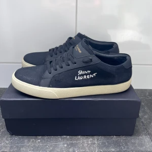 Svarta sneakers från Saint Laurent - Snygga svarta sneakers från Saint Laurent med vit sula och broderad logga på sidan. Allt og medföljer. Skick 9/10