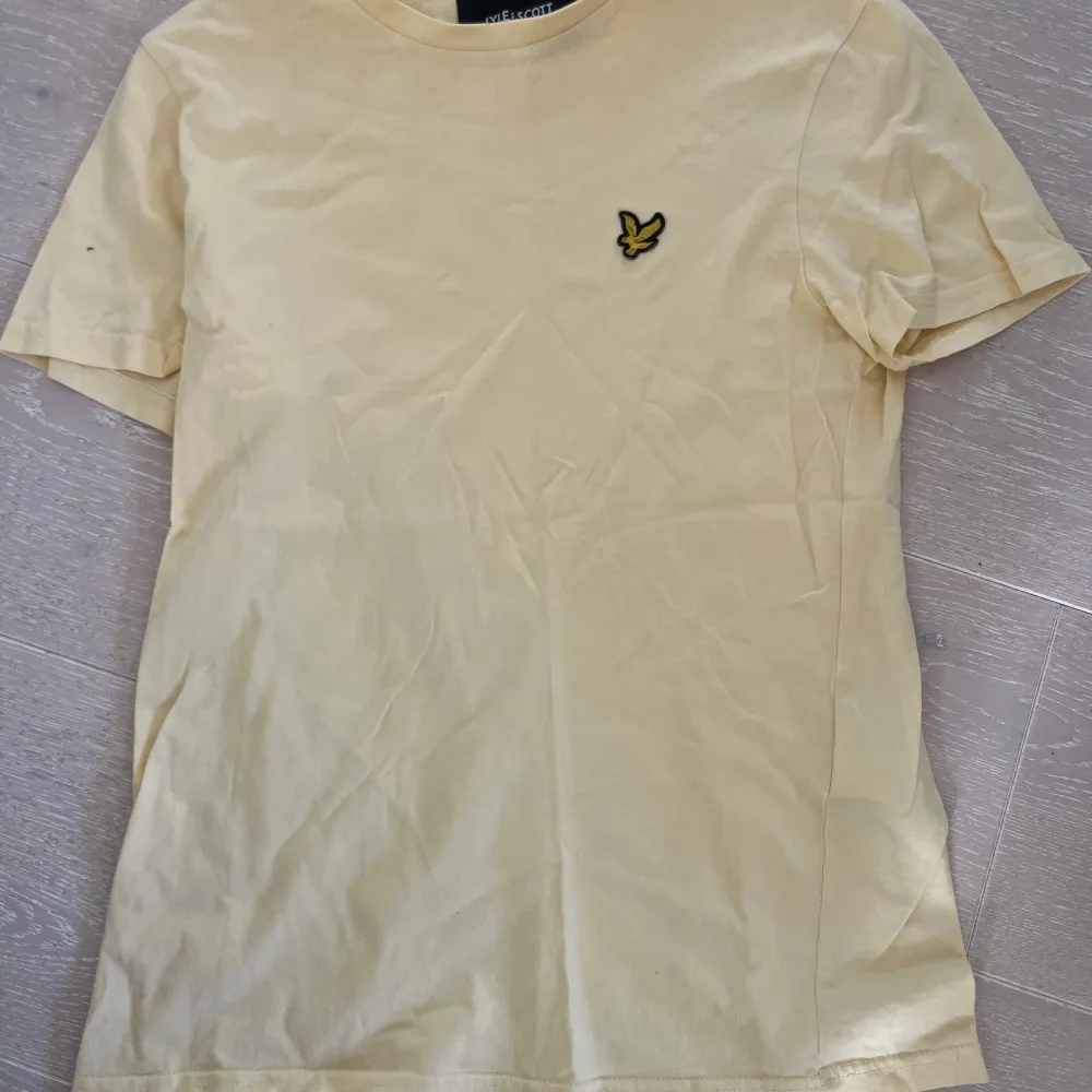 Säljer en gul t-shirt från Lyle & Scott med korta ärmar och en broderad logga på bröstet. Perfekt för en avslappnad stil. Passar bra till jeans eller shorts. Strl xs. Fint skick. Rök och djurfritt hem.. T-paidat.