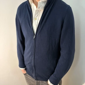 Mörkblå kofta från Pier One - Säljer en stilren mörkblå kofta från Pier One. Koftan har en dragkedja framtill och är tillverkad i ett mjukt material. Perfekt för lager-på-lager-stil och passar till många olika outfits. Plagget är M men sitter som M/S. Bra skick, men lite urtvättad . Modellen är 182cm/67kg.