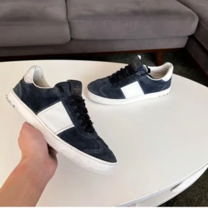Valentino sneakers i blå mocka - Snygga Valentino sneakers i blå mocka med vita detaljer och svart snörning. Perfekta för en stilren look. Skorna har en rund tå och en bekväm passform. Passar även 42