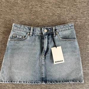 Blå jeanskjol från Bershka - Snygg blå jeanskjol från Bershka. Helt ny med prislapp kvar. Säljer då den inte riktigt passade. Ni ser måtten på bilderna. Tryck gärna på köp nu!!💕💕