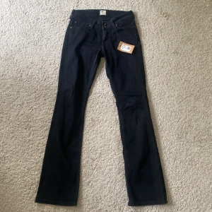 Svarta bootcut jeans från Lee - Snygga svarta bootcut jeans från Lee med klassisk femficksdesign och dubbla knappar i midjan. Perfekta för en stilren look. Såå såå fina men är tyvärr är små för mig💕💕😍helt nya