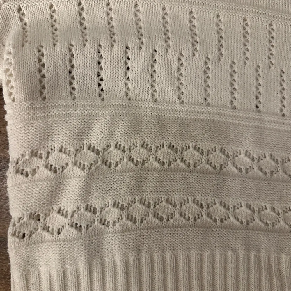 Säljer en stilren vit stickad tröja från ONLY med dekorativa hålmönster och ribbade detaljer. Tröjan har långa ärmar och en rund halsringning. Perfekt för en mysig look och att slänga på sig på sommarkvällarna . Neuletakit & Villapaidat.