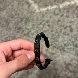 Svart armband med nitar från Valentino Garavani - Säljer ett stilrent svart armband från Valentino Garavani med silverfärgade nitar. Skick 9/10 och allt og följer med. Självklart äkta. Använda ett fåtal gånger.
