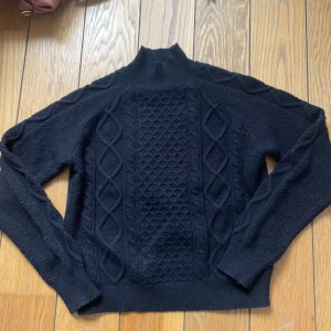 Svart stickad tröja  - Säljer en svart mjuk stickad tröja med ett snyggt flätmönster på framsidan