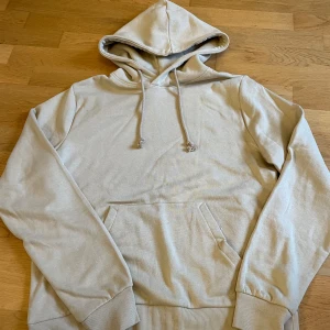 Beige hoodie från SOC - Säljer en beige hoodie från SOC i storlek S. Den har en klassisk design med en stor ficka framtill och justerbar huva med dragsko. Aldrig använd väldig fin gosig inuti.