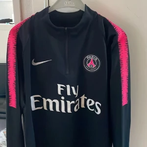 PSG långärmad Nike Dri-Fit tröja M - Paris Saint-Germain långärmad träningströja från Nike i svart med rosa detaljer längs ärmarna. Tröjan passar både killar och tjejer. Storlek M men passar S 