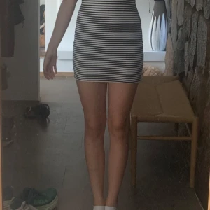 Randig kortklänning från Petrol Ind - Supersnygg kortklänning från Petrol Ind i marinblått och vitt med smala ränder. Klänningen har rund hals, korta ärmar och en tight passform som framhäver figuren. Perfekt för dig som gillar en enkel men stilren look.