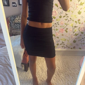 Svart kjol - Säljer en svart tight kortkjol med enkel och stilren design. Kjolen har en figurnära passform och är perfekt att matcha med crop tops eller oversized tröjor. Materialet känns mjukt och stretchigt, vilket gör den bekväm att bära hela dagen.