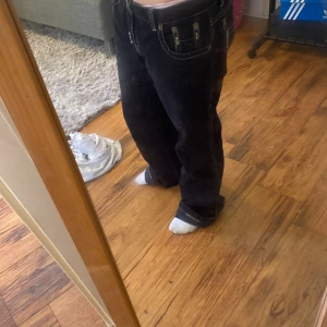 Svarta manchesterbyxor bootcut - Säljer ett par svarta manchesterbyxor med bootcut passform och snygga kontrastsömmar. Byxorna har klassiska fickor fram och bak samt låg midja. Perfekta för dig som gillar retrovibbar och vill ha ett par byxor som sticker ut lite extra.