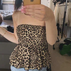 Jätte gullig topp har aldrig använt  - Säljer en superfin bandeau tubtopp med leopardmönster. Toppen är axelbandslös och har en volangig, lätt utsvängd nederdel som ger en snygg siluett. Perfekt för dig som vill sticka ut med ett djurmönster och en trendig look.