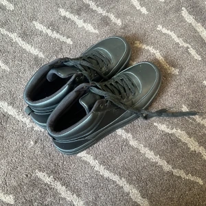 Svarta sneakers från Deakins - Svarta sneakers från Deans med klassisk design och högt skaft. Skorna har snörning, rund tå och platt sula. Ovandelen är i syntetmaterial och insidan är vadderad för extra komfort. Perfekta för dig som gillar en clean och stilren look.