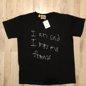 Svart Gallery Dept - Helt ny Svart t-shirt från Gallery Dept. med vit handskriven text 'I am sad I miss my friends' på framsidan och stor röd logga på ryggen. Klassisk passform och rund hals. Perfekt för dig som gillar streetwear med edge.