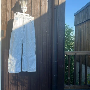 Vita wide jeans från Bershka - Säljer ett par vita wide jeans från Bershka med klassisk femficksdesign och raka, vida ben. Jeansen har hög midja och är tillverkade i ett kraftigare bomullstyg. Perfekta för dig som gillar en avslappnad och trendig look.