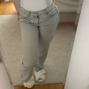 Ljusblå raka jeans från gina - Säljer ett par ljusblå jeans från gina med klassisk femficksdesign och raka ben. Jeansen har låg midja och en avslappnad passform, perfekta för en chill och stilren look. Tillverkade i mjukt denimtyg som är skönt att bära hela dagen.