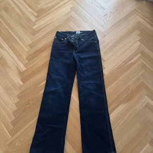 Mörkblå bootcut jeans 157 - Snygga mörkblå jeans från 157 med bootcut passform. Klassisk femficksdesign, kontrastsömmar och coola bakfickor med lock och knapp. Perfekta för dig som gillar en lite vidare siluett. Stolek S