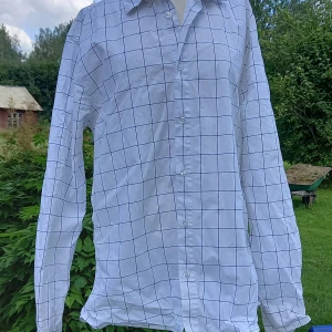 Vit rutig skjorta från Cubus, slim fit - Vit skjorta från Cubus med svart rutigt mönster. Slim fit-modell med stretch för extra komfort. Långärmad och klassisk krage, knäppning framtill. Tillverkad i 97% bomull och 3% elastan. Perfekt för dig som gillar stilrena och fräscha skjortor.