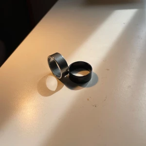 Två breda ringar i svart och silver - Säljer två stilrena ringar med bred design, en i blankt svart och en i klassisk silverfärg. Båda har en enkel, modern look och passar perfekt för dig som gillar minimalistiska accessoarer. Materialet känns robust och ringen sitter bekvämt på fingret. båda är i storlek 7 och när jag mätte med linjal så var de 17mm