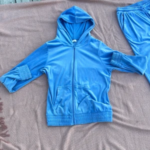 Blå mjukis sett från Teen Studio - Säljer ett blått mjukis sett från Teen Studio i supermjuk velour. Byxorna har resår och snörning i midjan, raka ben och fickor både fram och bak. Perfekta för chill dagar eller när du vill vara extra bekväm.