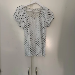 Vit prickig topp från Our Best Basics - Supersöt vit topp med svarta prickar har använts några gånger men är som ny hör av dig vid intresse! 