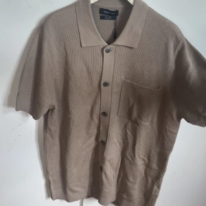 Beige kortärmad skjorta Massimo Dutti - Stilren beige skjorta från Massimo Dutti i 100% bomull. Skjortan har korta ärmar, ribbad struktur, klassisk krage, knäppning framtill och en bröstficka. Perfekt för dig som gillar en clean och avslappnad look. Cond 9.5/10. Nypris 600, vårat pris 450