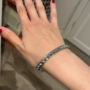 Silvrigt armband med nitar från Edblad - Snyggt armband i silverfärgad metall från Edblad med coola konformade nitar längs hela bandet. Stilren och edgy design som ger en tuff touch till din outfit. Perfekt för dig som gillar detaljer som sticker ut.