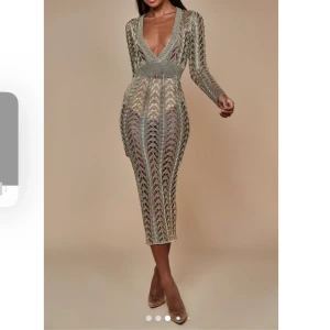 Beige stickad / virkad klänning med öppen rygg - Supersnygg beige stickad klänning med lång ärm och v-ringning. Klänningen har ett genombrutet mönster och en öppen rygg som ger en extra wow-effekt. Den är figurnära och går till under knäna – perfekt för dig som vill sticka ut. Från Sorelleuk metallic gold dress