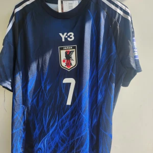 Japan Mitoma #7 fotbollströja Adidas - Japan landslagströja från Adidas med Mitoma och nummer 7. Tröjan är marinblå med blå grafiskt mönster, vita detaljer och emblem på bröstet. Korta ärmar och klassiska Adidas-ränder på axlarna. Materialet är lätt och andas, perfekt för fotboll eller support.Size Xl(passar även L) Det är en Remake som menas att den inte är äkta. 