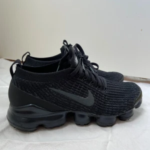 Nike Vapormax Flyknit Triple Black - Säljer ett par helsvarta Nike Vapormax Flyknit med stickad ovandel och ikonisk bubblig sula. Har använt skorna max tre gånger. Pris kan diskuteras. 