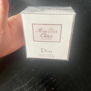 Miss Dior Chérie Eau de Parfum 100ml -  DISCONTINUED!!                                                          Miss Dior Chérie Eau de Parfum från Dior i en elegant vit och ljusrosa kartong. Flaskan rymmer 100 ml och är en klassisk doft med feminina och fräscha toner. Förpackningen är fyrkantig och stilren, perfekt för dig som gillar lyxiga parfymer.