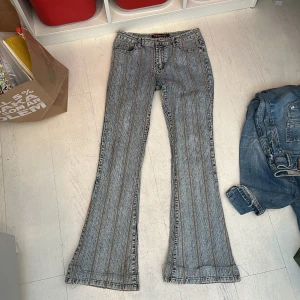 Blå jeansbyxor med bruna sömmar - Säljer ett par blå jeansbyxor med bruna dekorativa sömmar och bootcut-modell. 