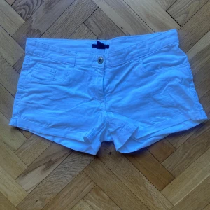 Vita lowwaist shorts  - Snygga vita shorts från H&M med klassisk femficksdesign och knappstängning framtill. De är tillverkade i bomull och har en normal passform med låg midja. Perfekta för varma sommardagar.