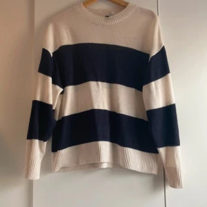 Randig stickad tröja i blått och vitt - Säljer en stickad tröja med breda marinblå och vita ränder. Tröjan har rund halsringning, långa ärmar och ribbade muddar vid ärmslut och nederkant. Bra skick💗har tvättats några gånger så det har påverkat den lite