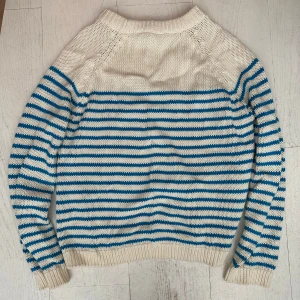 Randig stickad tröja i vitt och blått - Säljer en mysig stickad tröja med vita och blå ränder. Tröjan har lång ärm, och ribbade muddar!☺️ 