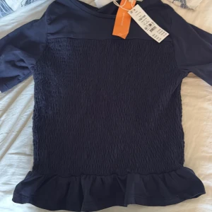 Mörkblå blus med volang - Söt marinblå smockad topp från gina. Helt ny med prislapp kvar! Orginalpris 219 och säljs inte längre