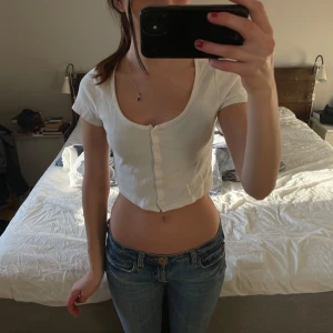 Vit croppad topp med knappar - Säljer en supersöt vit croppad topp. 